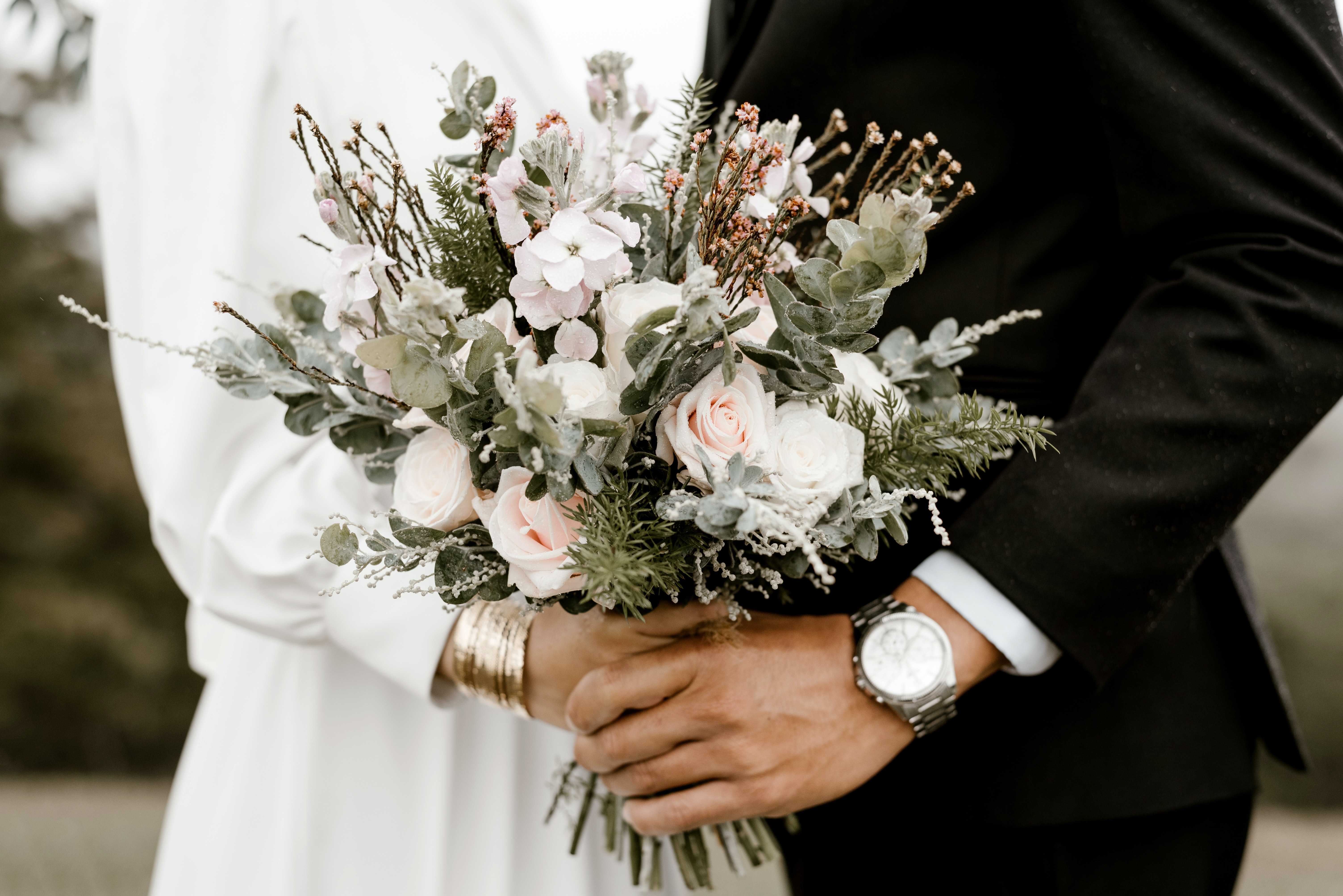Husband holding hand of wife who is holding a boquet
